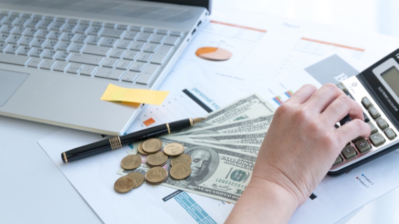 Cash, coins, and a calculator on a desk showing mathematics in building financial strategies