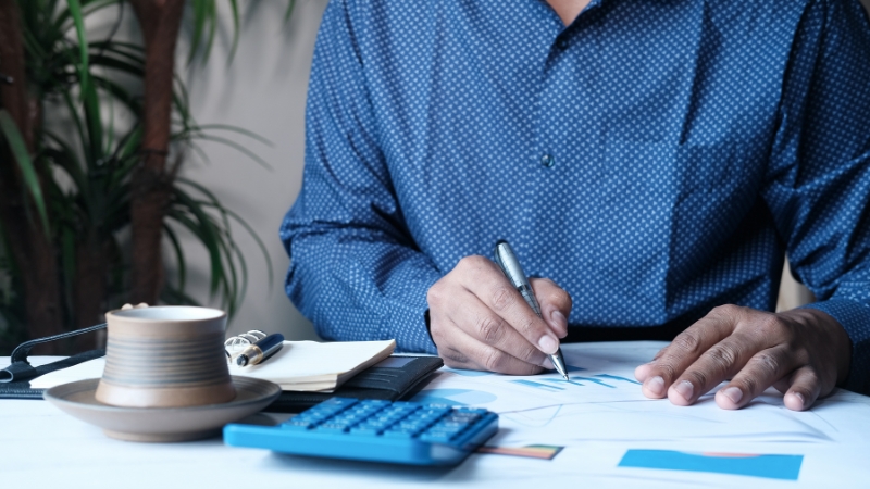 Man reviews charts with a pen and calculator, showing measuring risk to manage it