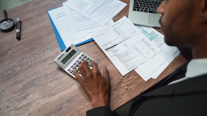 Man with calculator and financial papers showing time, growth, and compounding in building financial strategies