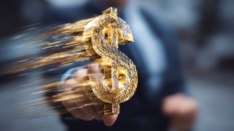 Glowing dollar symbol moving forward in front of a businessperson in a blurred background