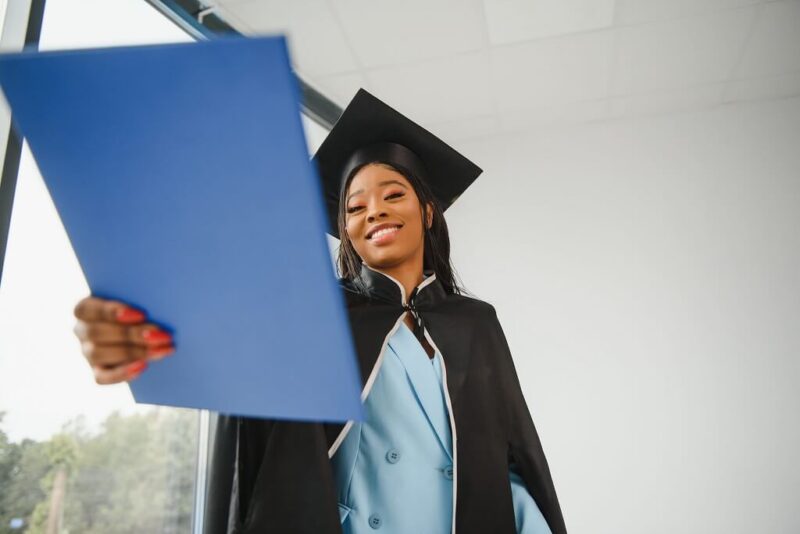 Graduate in cap and gown looking at her diploma after completing university