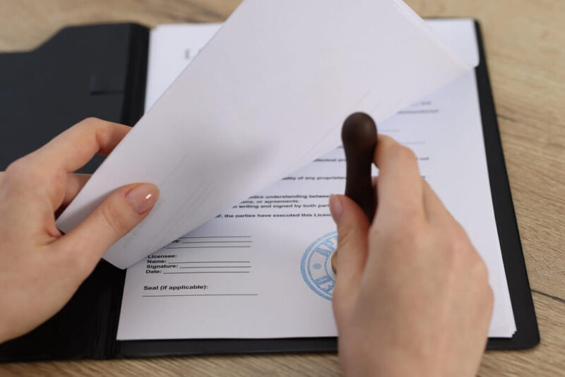 Close-up of hands reviewing stamped official documents in a folder